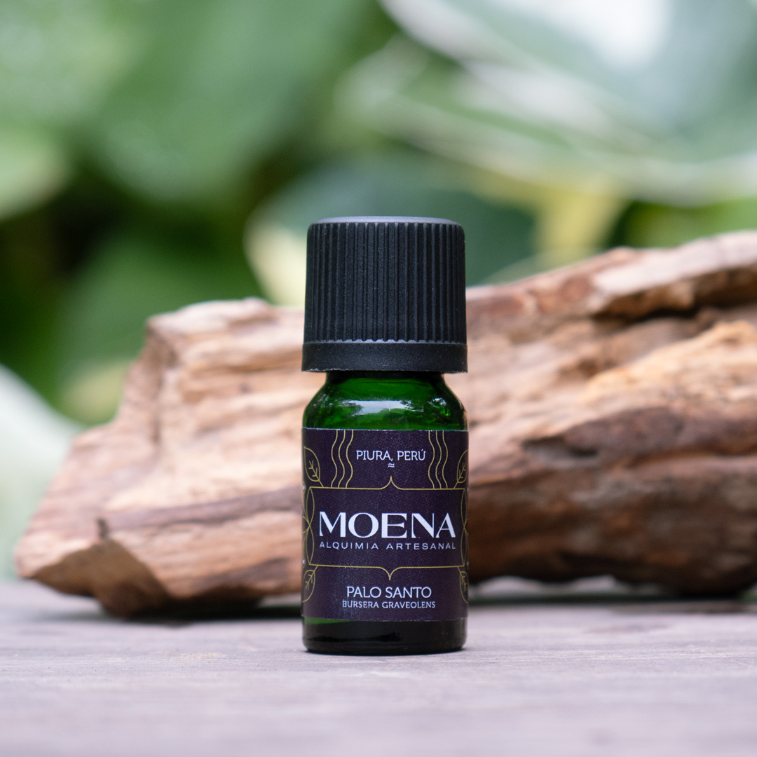 Bottle of Moena Palo Santo essential oil on a wooden surface with a blurred natural background