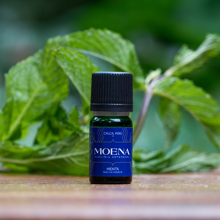 Blue bottle of MOENA Peppermint Essential Oil with mint leaves in the background